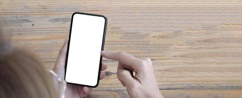 image de maquette téléphone portable à écran blanc vierge. main de femme tenant des textos à l'aide de mobile sur le bureau au bureau à domicile. photo