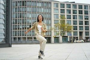 content gens dans ville. optimiste Jeune fille dansant sur rue dans écouteurs, écoute la musique dans écouteurs photo