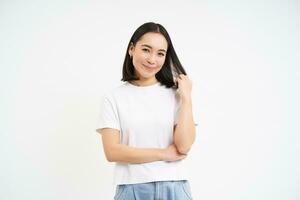 portrait de Jeune sur de soi asiatique femme, regards avec confiance des stands dans décontractée T-shirt, isolé sur blanc Contexte photo