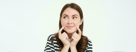 beauté et femmes concept. Jeune souriant femme, montrant sa mignonne fossettes sur visage et à la recherche content, positif émotion, magnifique visage sans pour autant les imperfections, permanent plus de blanc Contexte photo