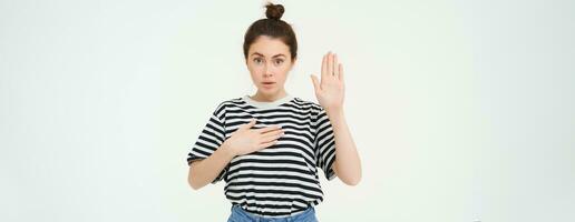 image de femme fait du promesse, jure, soulève un main et met paume sur cœur, étant honnête, des stands plus de blanc Contexte photo