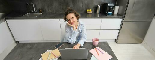 magnifique travailleur indépendant fille travaux de maison. Jeune femme en ligne en étudiant, en train de regarder cours sur site Internet, à la recherche à portable écran photo