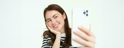 portrait de Jeune femme prise selfies sur téléphone intelligent, posant pour photo,. en utilisant mobile téléphone app pour prise marrant et mignonne des photos, isolé sur blanc Contexte photo