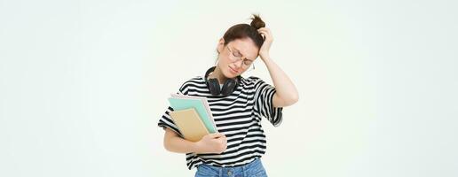 déçu Jeune femme, à la recherche fatigué ou bouleversé, portant lunettes, en portant étude matériel, les documents et des cahiers, des stands plus de blanc Contexte photo