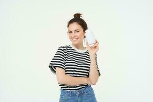 soins de santé et bien-être. Jeune femme en portant bouteille avec vitamines, diététique suppléments, traitement pour bien peau et cheveux, permanent plus de blanc Contexte photo