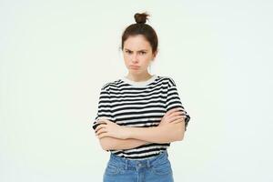 portrait de en colère, offensé Jeune femme, traverser bras sur poitrine et faire la moue, à la recherche à caméra avec insulté visage expression, isolé plus de blanc Contexte photo