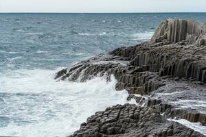 rocheux rivage formé par de colonne basalte contre le toile de fond de une orageux mer, côtier paysage de le kuril îles photo