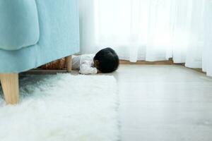 peu asiatique les enfants enfant en jouant cacher et chercher derrière le canapé, adorable enfant ayant amusement dans le maison. content famille avoir amusement avec enfants, activité, apprentissage, activité, jeu, méditation photo