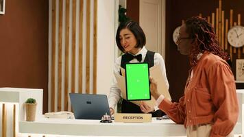 se lasser touristique en portant chrominance clé vert écran moquer en haut tablette à Hôtel accueil bureau après longue vol, attendre pour pièce Paiement à être traité. client dans recours foyer Faire vérifier dans photo