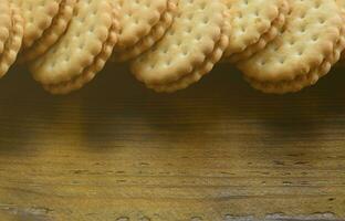 un biscuit sandwich rond fourré à la noix de coco se trouve en grande quantité sur une surface en bois marron. photo de friandises comestibles sur un fond en bois avec espace de copie