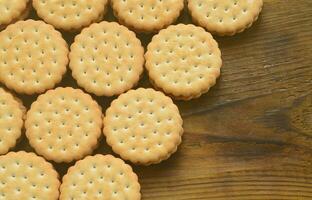 un biscuit sandwich rond fourré à la noix de coco se trouve en grande quantité sur une surface en bois marron. photo de friandises comestibles sur un fond en bois avec espace de copie