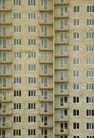 motif texturé d'un mur de construction de maison résidentielle en pierre blanche russe avec de nombreuses fenêtres et balcon en construction photo