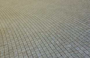 dalles de pavage de couleur grise dans le trottoir de la rue piétonne. motif pavé rugueux avec de nombreuses pierres de forme carrée photo