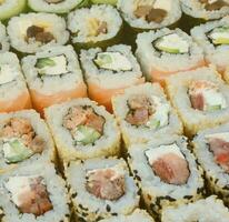gros plan sur beaucoup de rouleaux de sushi avec différentes garnitures. photo macro de plats japonais classiques cuits. image de fond