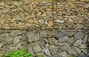 photo de nombreuses gabions. le engrener cellules de le cubique forme sont rempli avec Montagne des pierres de divers formes cette laisser l'eau par le pluie, mais protéger le route de chute des pierres