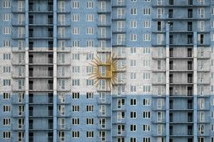 Argentine drapeau représenté dans peindre couleurs sur à plusieurs étages résidentielle bâtiment en dessous de construction. texturé bannière sur brique mur Contexte photo