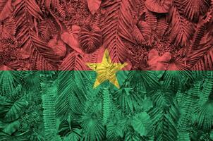 burkina faso drapeau représenté sur beaucoup feuilles de monstera paume des arbres. branché à la mode toile de fond photo