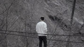 arrière vue de une homme permanent à le bord de un l'automne gris sale pente. Stock images. Jeune homme à la recherche réfléchi. photo