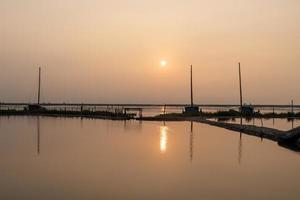 au lever du soleil le matin, l'eau de mer reflète le bateau de pêche photo