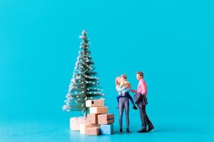 personnes miniatures, famille heureuse debout à côté d'un arbre de noël photo