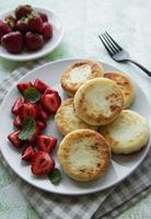 crêpes au fromage cottage, beignets de ricotta sur plaque en céramique avec fraise fraîche.