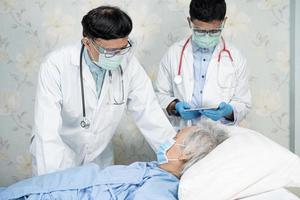 une équipe de médecins asiatiques vérifie la maladie chez la vieille patiente âgée pour motiver une nouvelle normalité pour traiter l'infection par le coronavirus covid-19 dans la salle d'hôpital