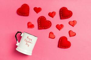 Haut vue de rouge textile cœurs éclabousser en dehors de une tasse sur coloré Contexte. content la Saint-Valentin journée concept photo