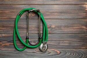 Haut vue de vert stéthoscope sur foncé en bois Contexte. médical examen concept photo