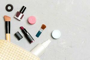 vue de dessus des produits de maquillage tombés du sac de cosmétiques sur fond de ciment. concept cosmétique avec espace pour votre conception photo