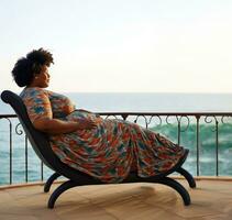 ai généré joufflu adulte foncé écorché femme dans longue coloré robe mensonge sur salon chaise sur rivage. photo