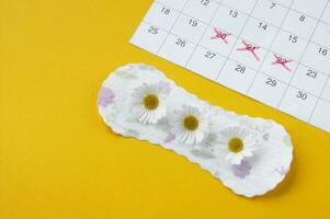 menstruel tampons avec camomille sur menstruation période calendrier sur Jaune Contexte. photo