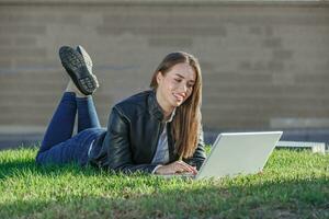 souriant femelle pigiste mensonge sur estomac avec pieds en haut en utilisant netbook photo