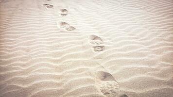empreintes sur plage avec une ondulé modèle établi par le vent, chaud sablonneux plage Contexte avec combat bottes pied impressions photo