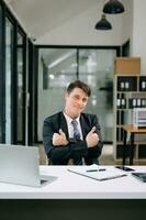 Jeune homme d'affaire travail à Bureau avec ordinateur portable, tablette et prise Remarques sur le papier. photo