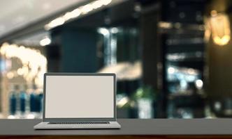 écran blanc d'ordinateur portable sur une table en bois avec un arrière-plan estompé. photo