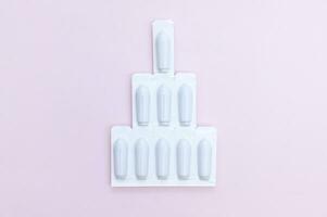 gynécologique médicaments pour aux femmes santé dans forme de suppositoire, capsules sur rose Contexte. photo