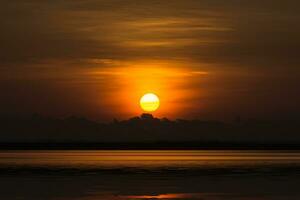lever du soleil sur Orange ciel et foncé nuage à le lac. photo