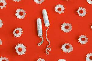 hygiénique médical femelle tampon avec camomille autour sur une rouge Contexte. photo