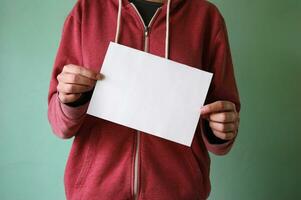 une Jeune homme détient un vide feuille de papier. photo