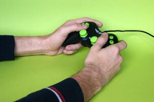 Masculin mains tenir une manette de jeu dans lumière vert Contexte. photo