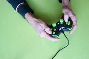 Masculin mains tenir une manette de jeu dans lumière vert Contexte. photo