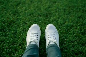 ai généré mode mode de vie pieds dans blanc baskets sur luxuriant vert herbe photo