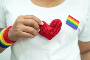 asiatique Dame portant arc en ciel drapeau bracelets et tenir cœur, symbole de lgbt fierté mois célébrer annuel dans juin social de gay, lesbienne, bisexuel, transgenres, Humain droits. photo