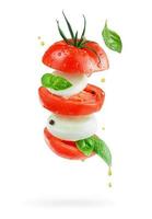 Salade italienne volante caprese avec fromage mozzarella, tomates et basilic isolé sur fond blanc. photo