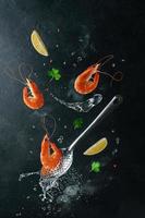 crevettes tigrées volantes avec des ingrédients sur une écumoire et de l'eau bouillie. conception créative de la cuisine des fruits de mer