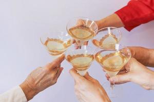 nouvel an célébrant les mains avec des verres de vin mousseux blanc. noël, famille, amis, fête, concept du nouvel an photo