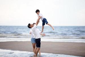 parents actifs et personnes activité de plein air pendant les vacances d'été et les vacances avec les enfants. une famille heureuse et son fils se promènent en s'amusant au coucher du soleil sur la plage de sable.