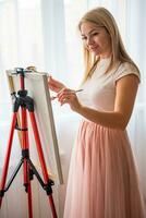 jolie Jeune femme artiste avec palette et brosse La peinture abstrait rose image sur Toile à maison. art et la créativité concept. haute qualité photo