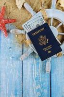 le temps de la roue du capitaine du marin pour voyager concept coquillages dans le sable de la plage plus de cent billets d'un dollar passeport américain photo