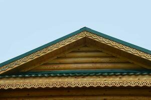 le toit de une en bois maison avec magnifique décoratif sculptures. élément de le façade de une en bois marron maison. photo